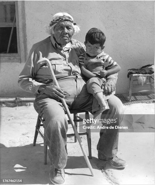 Portrait of an elderly man with his grandson sitting on his leg, southwest America, mid twentieth century.