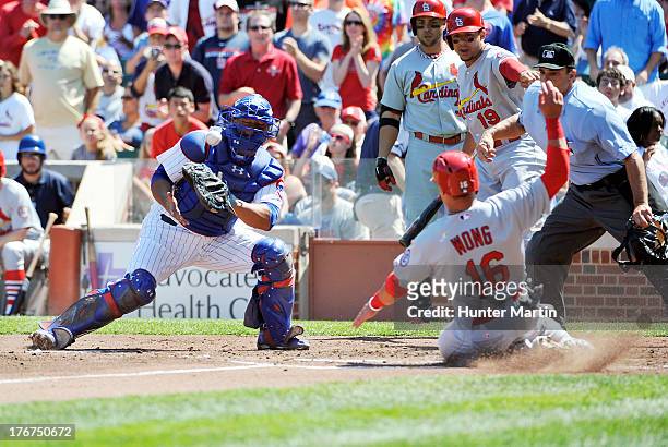 Kolten Wong of the St. Louis Cardinals scores a run as Welington Castillo of the Chicago Cubs tries to make a tag during the second inning on August...