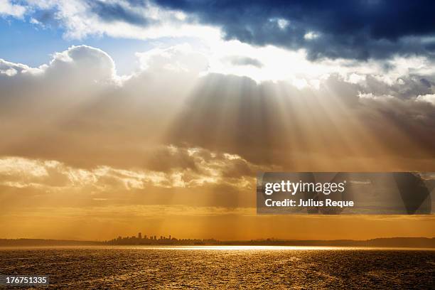 light rays from clouds above the city - sunbeam clouds stock pictures, royalty-free photos & images