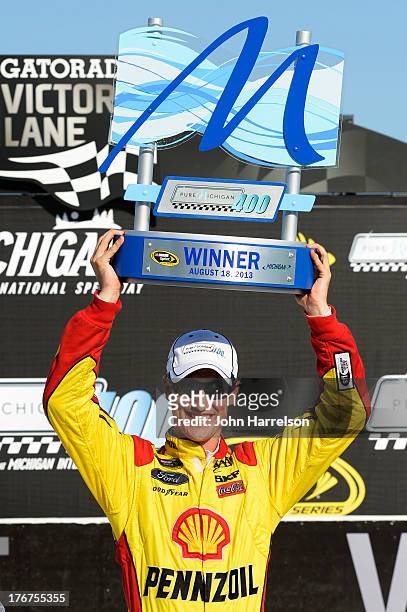 Joey Logano, driver of the Shell-Pennzoil Ford, celebrates the trophy in Victory Lane after winning the NASCAR Sprint Cup Series 44th Annual Pure...