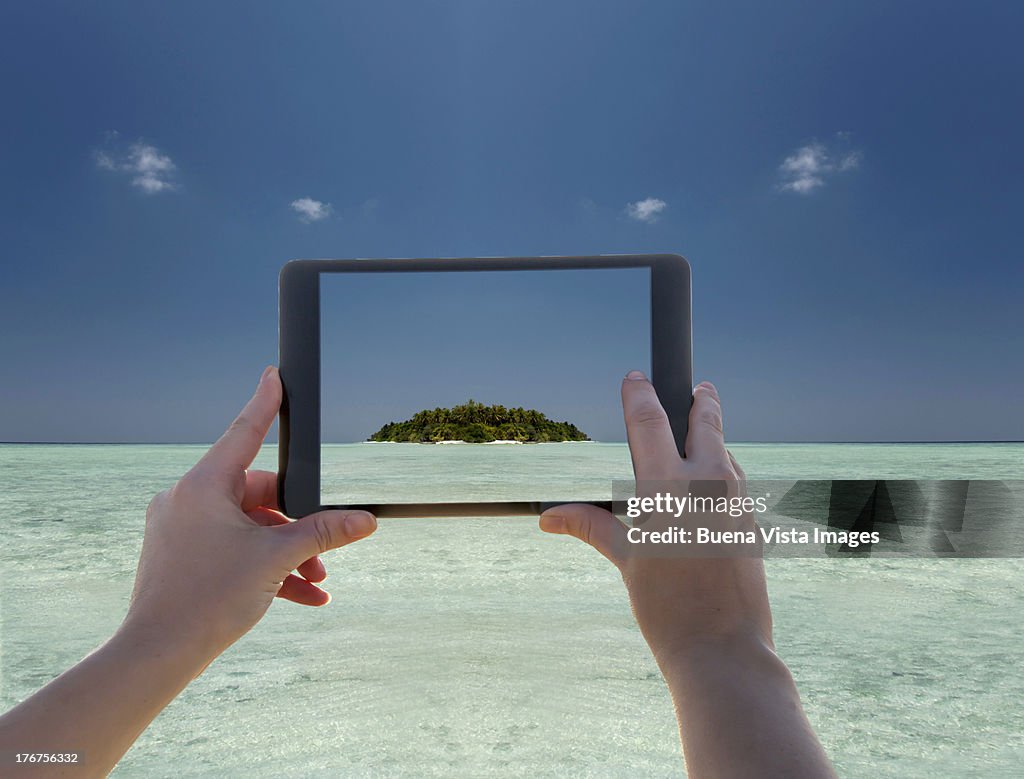 Woman's hand with tablet photographing a tropical