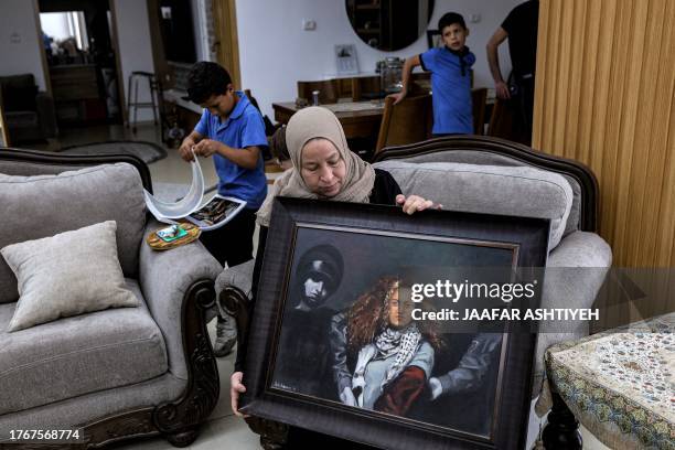 Nariman Tamimi, mother of detained Palestinian activist Ahed Tamimi, holds a framed painting depicting her daughter as she sits in their family home...