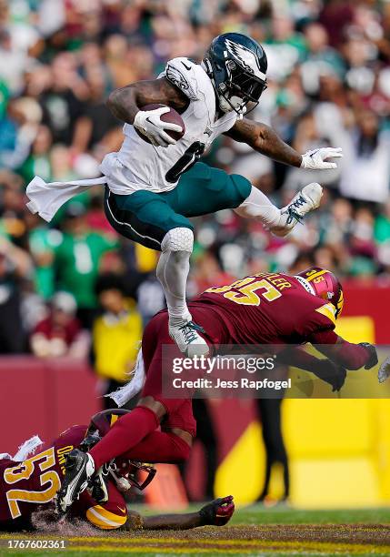 Andre Swift of the Philadelphia Eagles hurdles Percy Butler of the Washington Commanders in the third quarter at FedExField on October 29, 2023 in...