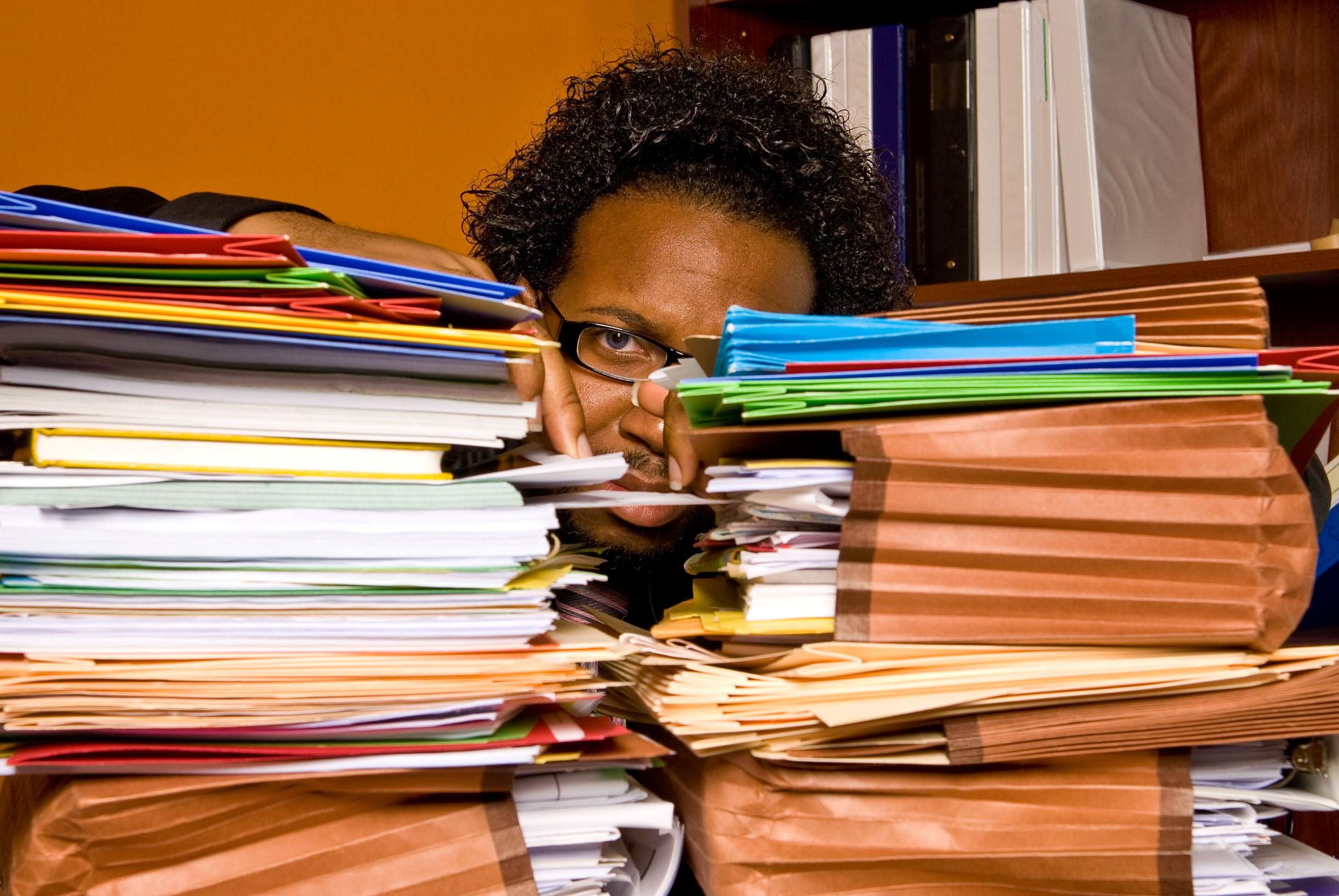 African American male buried behind a pile of folders African American male buried behind a pile of folders