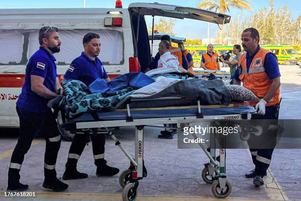 Egyptian paramedics transfer on a gurney an injured Palestinian woman on the Egyptian side of the Rafah border crossing with the Gaza Strip in the...