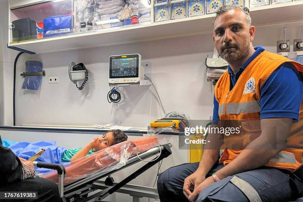 Paramedic sits next to an injured Palestinian child lying in an ambulance on the Egyptian side of the Rafah border crossing with the Gaza Strip in...