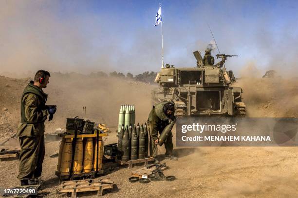 An Israeli army soldier carries rounds from a stockpile towards a stationed self-propelled artillery howitzer firing from a position near the border...