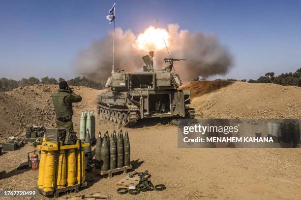 An Israeli army soldier covers his ears as a self-propelled artillery howitzer fires rounds from a position near the border with the Gaza Strip in...