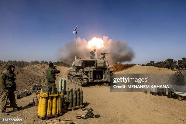 Israeli army soldiers cover their ears as a self-propelled artillery howitzer fires rounds from a position near the border with the Gaza Strip in...