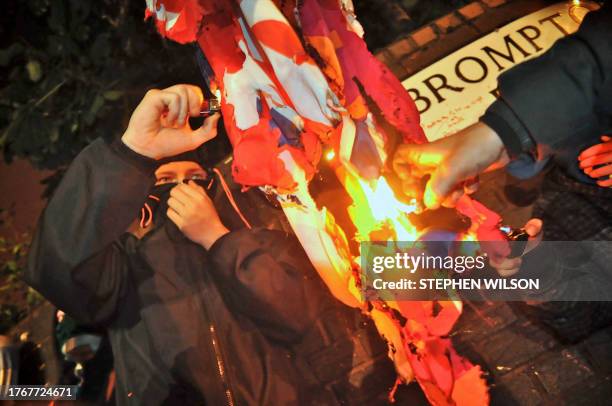 Masked nationalist sets fire to a Union Jack flag om July 14, 2010 during the third night of Nationalist rioting in Belfast. The rioting started the...