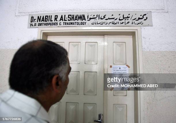 Palestinian man looks at an announcment taped at the door of Dr. Nabil al-Shawa's private medical practice and declaring it closed in Gaza City, 28...