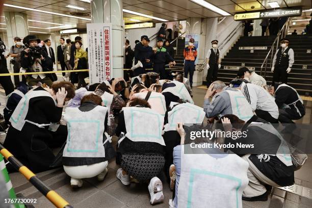 People huddle and cover their heads during an evacuation drill conducted at a subway station in Tokyo's Nerima Ward on Nov. 6 under the scenario that...