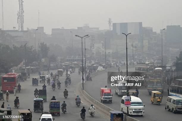 Commuters make their way through a busy street amid smoggy conditions in Lahore on November 7, 2023.