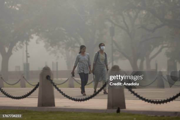 Masked commuters make their way past the India Gate amid smoggy conditions in New Delhi, India on November 07, 2023. Air Quality Index between 401...