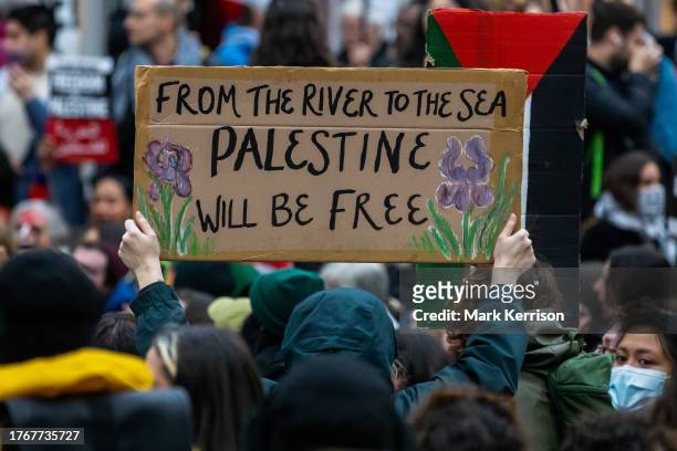Pro-Palestinian activist holds up a sign reading 'From The River To The Sea Palestine Will Be Free' during a sit-down protest inside Charing Cross...