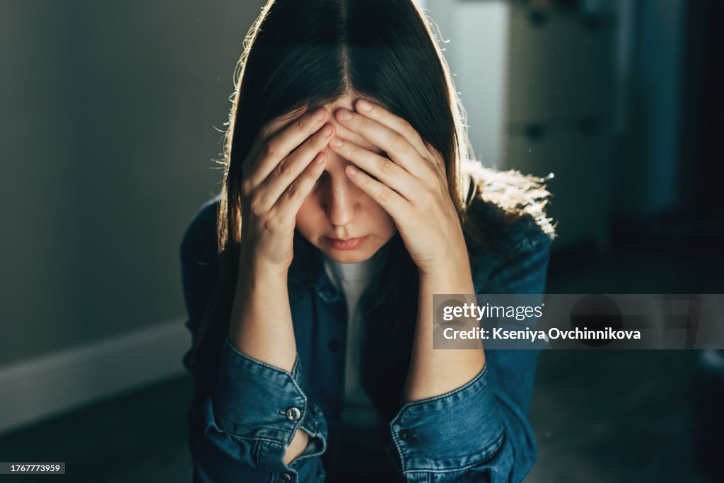 Silhouette of sad and depressed woman sitting on the floor at home