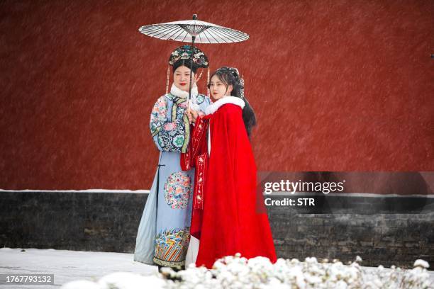 This photo taken on November 6, 2023 shows people taking photos as it snows in Shenyang, in China's northeastern Liaoning province. / China OUT