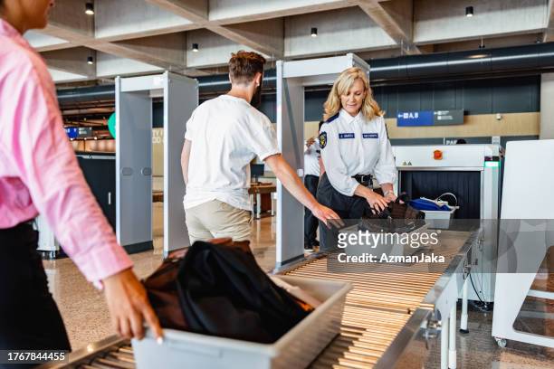 pasajero masculino caucásico empujando una bandeja para escanear equipaje de rayos x - security check fotografías e imágenes de stock