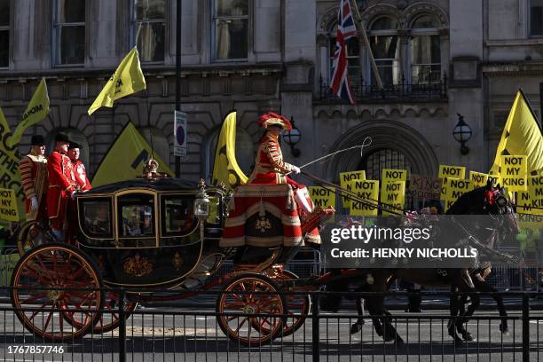 The Imperial State Crown is taken in the Queen Alexandra's State Coach past protesters holding "Not My King" placards, from the anti-monarchy group...