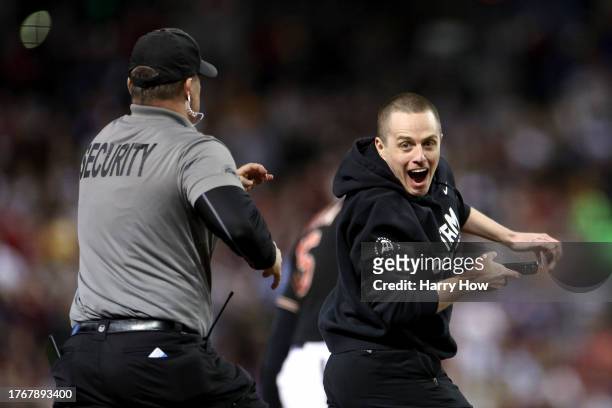 Security chases after a fan who ran onto the field in the fifth inning during Game Four of the World Series between the Texas Rangers and the Arizona...