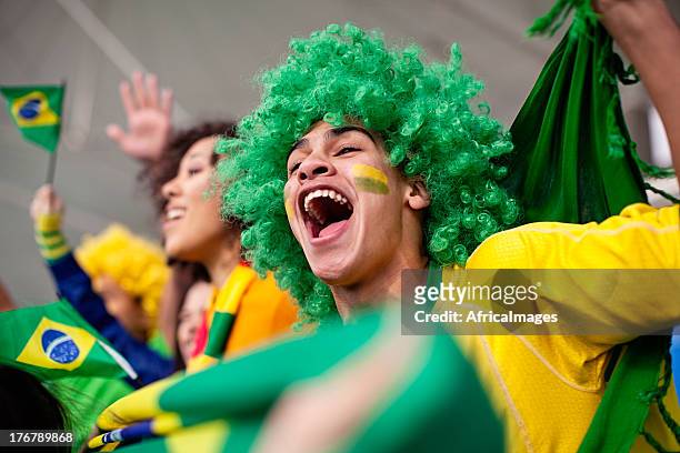 euphorique supporter brésilien en regardant un match de football américain - coupe du monde de football photos et images de collection