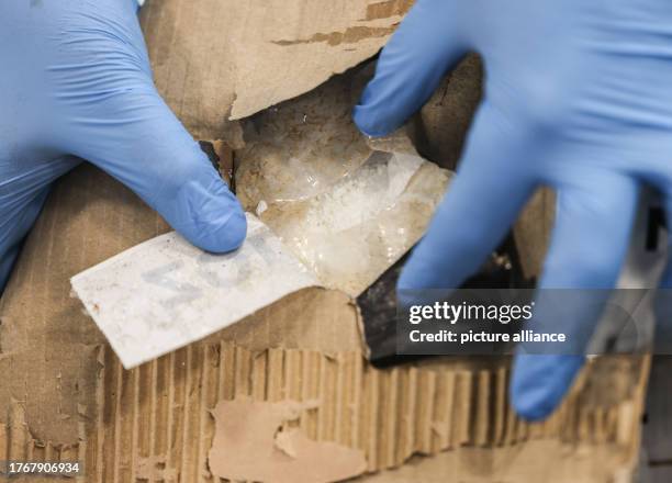 November 2023, North Rhine-Westphalia, Cologne: An employee of the Cologne Main Customs Office shows a stash of cocaine in a cardboard box from a...