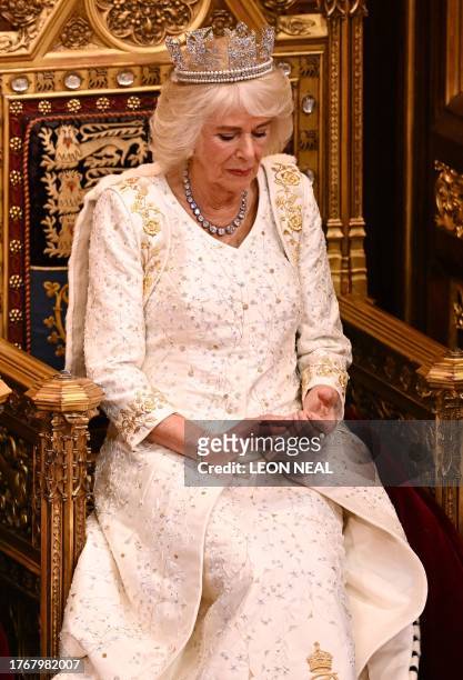 Britain's Queen Camilla, wearing the George IV State Diadem, listens as Britain's King Charles III reads the King's speech in the House of Lords...