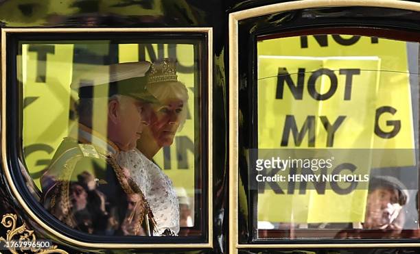 Britain's King Charles III and Britain's Queen Camilla travel in the Diamond Jubilee State Coach past protesters holding "Not My King" placards, from...