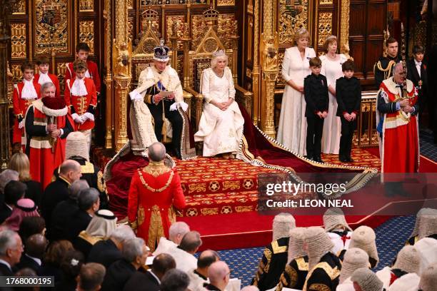 Britain's King Charles III, wearing the Imperial State Crown and the Robe of State, sits beside Britain's Queen Camilla, wearing the George IV State...