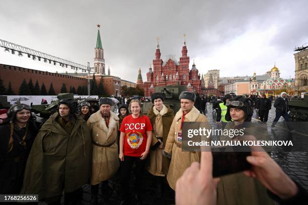 Woman wearing a T-shirt with the USSR logo poses with artists wearing WWII military uniform at an open air interactive museum at The Red Square in...