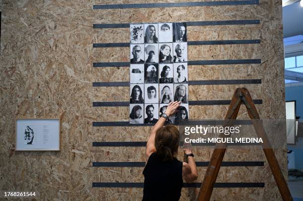 Woman hangs pictures, made with a giant camera obscura installed by Argentinian photographer Vivian Galban at a stand, two days before the opening of...