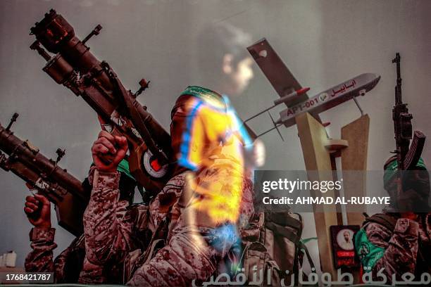 Reflection shows a boy walking past a poster in a shop window showing a fighter of the Izzedine al-Qassam Brigades, the military wing of the...