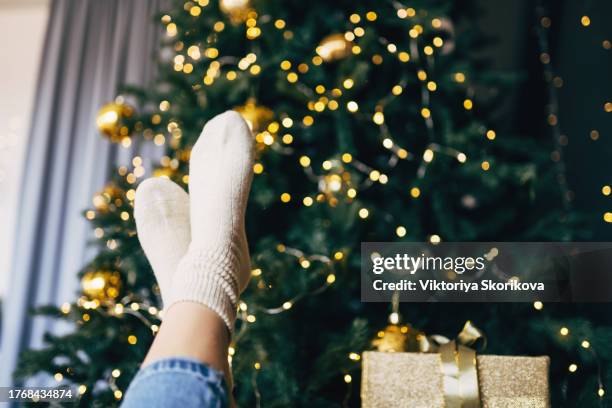 socks of caucasian woman with feet on table near christmas tree - christmas stress stock pictures, royalty-free photos & images