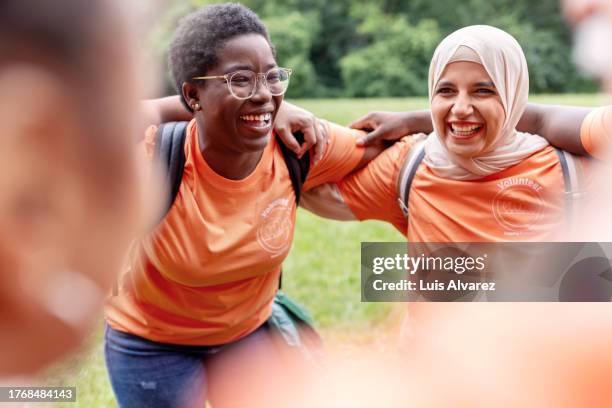 group of volunteers gather in a circle before cleaning up their community - responsabilité sociale photos et images de collection