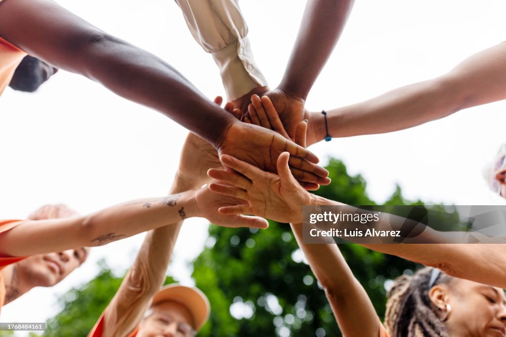 Multiracial volunteers stacking hands during environmental cleanup program