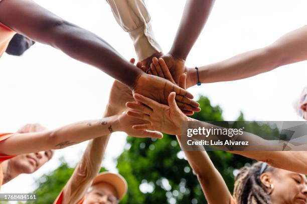 multiracial volunteers stacking hands during environmental cleanup program - angariação de fundos imagens e fotografias de stock