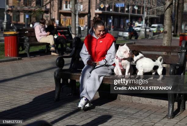 Woman sits on a bench with dogs in central Kyiv, November 7, 2023.