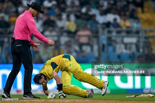 Australia's Glenn Maxwell falls on the ground after a muscle cramp during the 2023 ICC Men's Cricket World Cup one-day international match between...