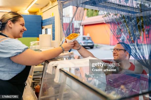 trabajador del servicio de alimentos sirviendo giroscopios a un joven en la calle - stand fotografías e imágenes de stock
