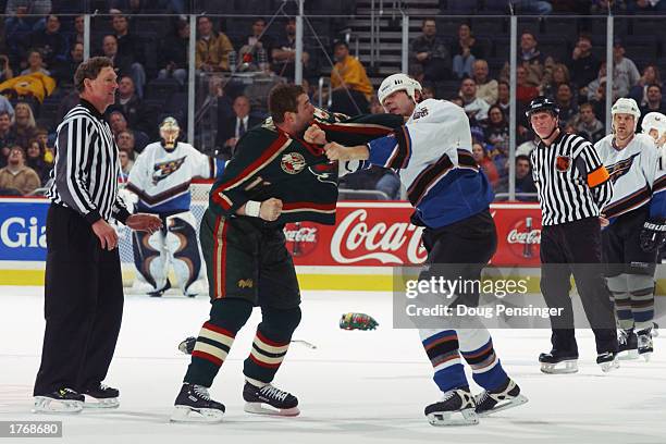 Linesman Kevin Collins, left, watches as Matt Johnson of the Minnesota Wild and Alex Henry of the Washington Capitals mix it up during the NHL game...