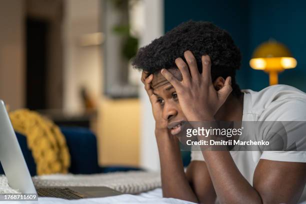 portrait sad upset sad african american guy has problems, poor financial results looking at laptop. - stock trader upset 個照片及圖片檔