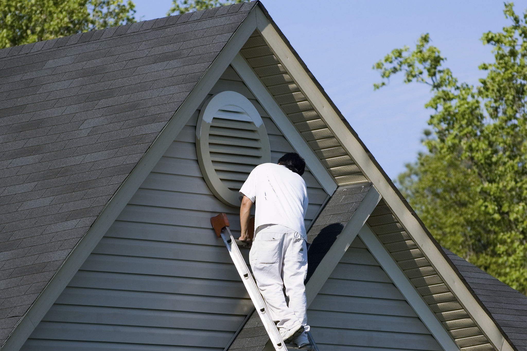 Painter working at roofline Painter working at roofline