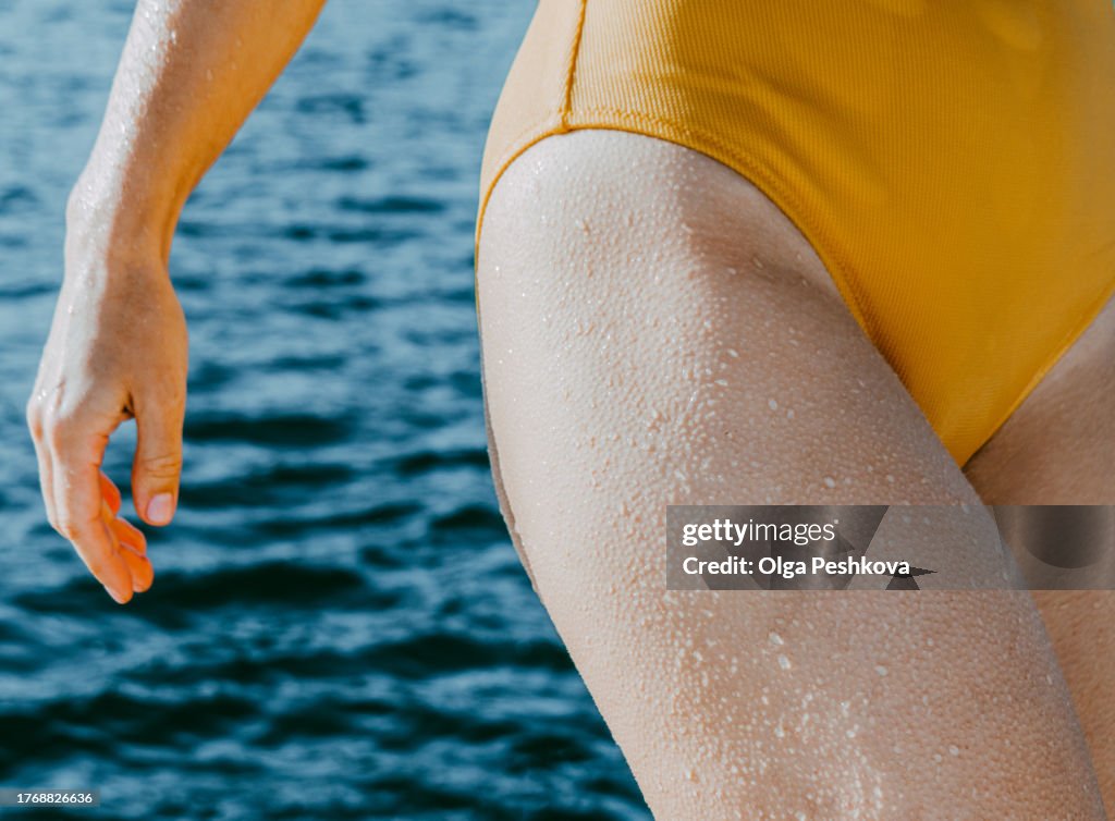 Unidentified young woman in a yellow swimsuit with goosebumps all over her body