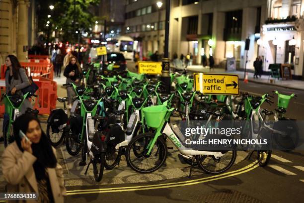 Pedestrians negotiate their way around Lime e-bikes parked on the pavement and on the road in central London on November 7, 2023. The San Francisco...