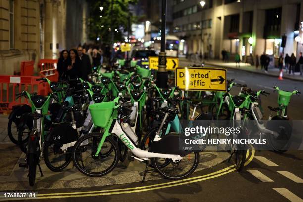 Pedestrians negotiate their way around Lime e-bikes parked on the pavement and on the road in central London on November 7, 2023. The San Francisco...