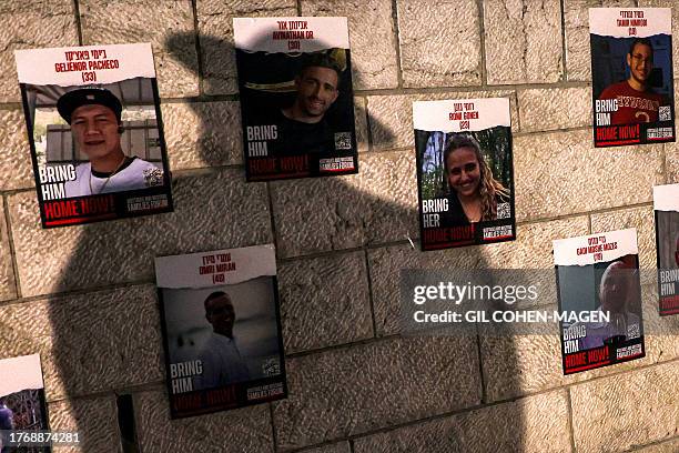 The shadow of an ultra-Orthodox Jewish man is pictured before posters hanging on a wall, identifying some of the hostages abducted by Palestinian...
