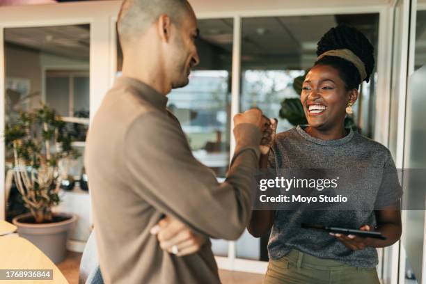 young businesswoman smiling cheerfully and doing fist bump with project partner in coworking office - fist bump stock pictures, royalty-free photos & images