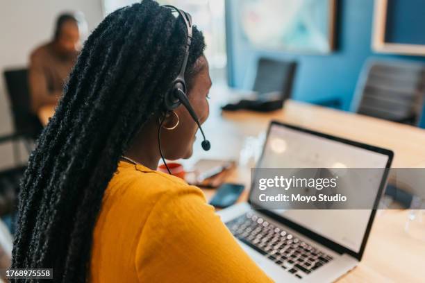 rückansicht einer geschäftsfrau mit headset, die mit einem laptop auf dem schreibtisch arbeitet - obscured face stock-fotos und bilder