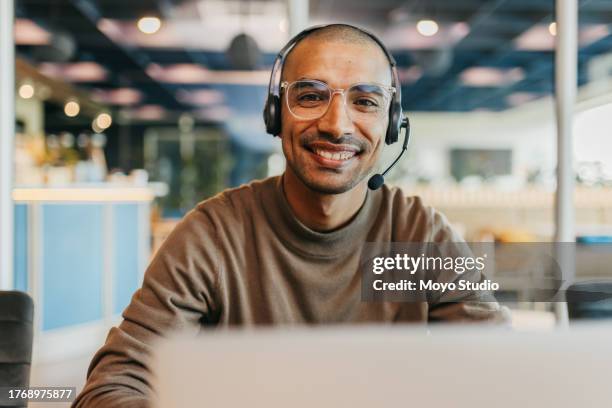 vorderansicht eines geschäftsmannes, der im callcenter-büro fröhlich in die kamera lächelt - headset stock-fotos und bilder