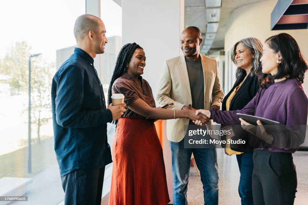 Group of multiracial business partners shaking hands in coworking office space
